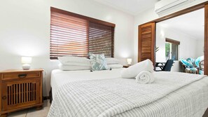 A hotel room with a bed, bedside tables, a mirror, and a view of the outdoors. - Sea Views on Kennedy (South Mission Beach)