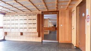 A hotel lobby with wooden lockers, a tiled floor, and a door leading to a corridor. - Rã©sidence Les Crãªts 1 - Val-d'isã¨re (Val-d'Isere)