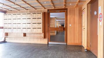 A hotel lobby with wooden lockers, a tiled floor, and a door leading to a corridor.
