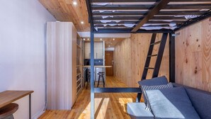 A compact room with a wooden floor, a sofa with cushions, a small table, and a ladder against the wall. - Rã©sidence Les Crãªts 1 - Val-d'isã¨re (Val-d'Isere)