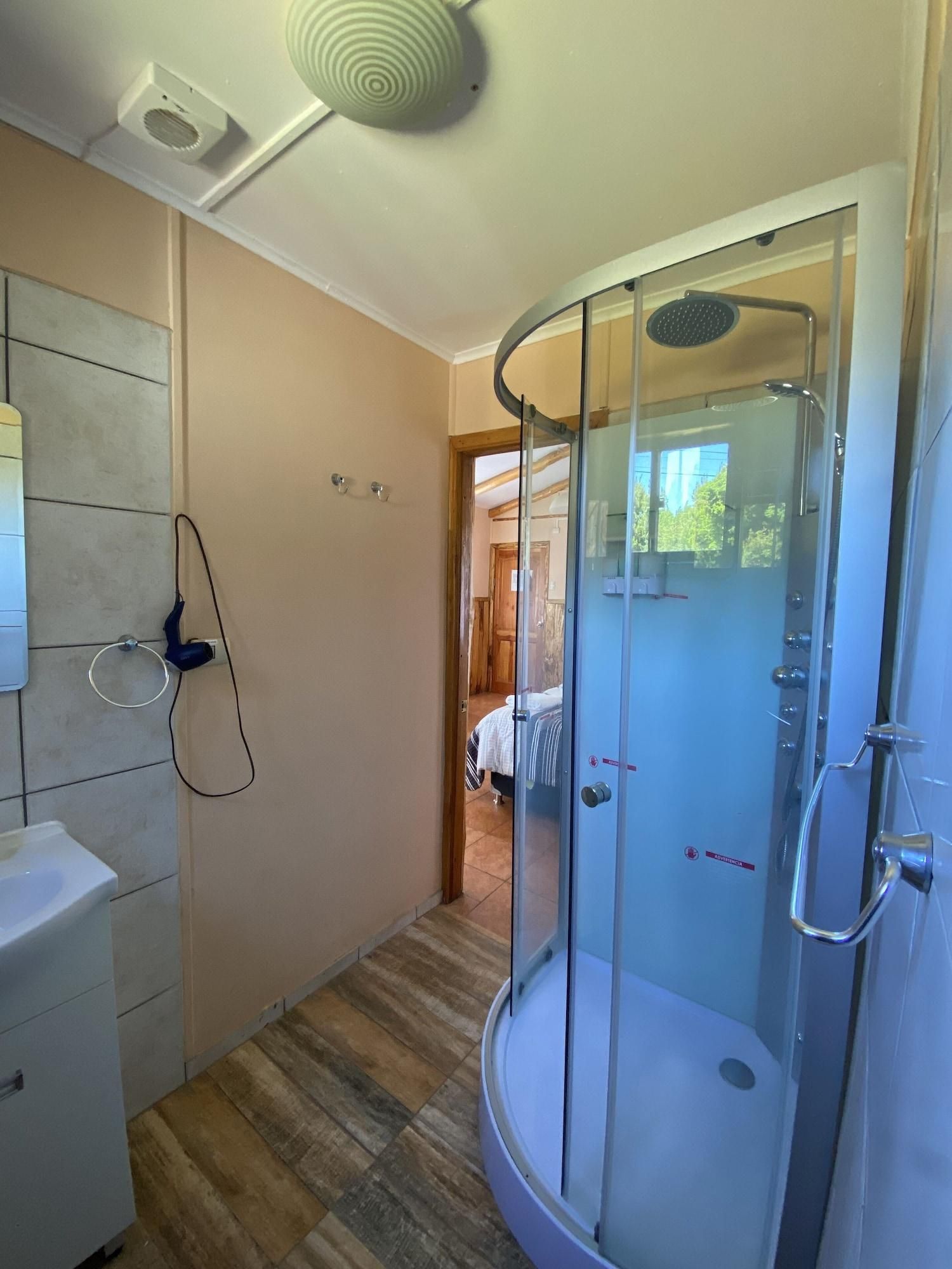 A modern bathroom with a glass shower enclosure, a white sink, and a towel ring on the wall.