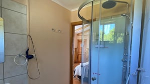 A modern bathroom with a glass shower enclosure, a white sink, and a towel ring on the wall.
