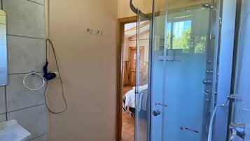 Un baño moderno con cabina de ducha de vidrio, un lavabo blanco y un aro para toallas en la pared.