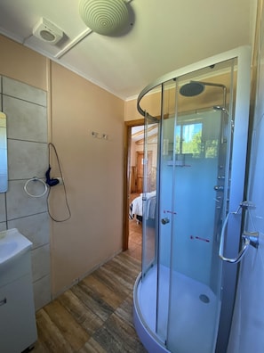 A modern bathroom with a glass shower enclosure, a white sink, and a towel ring on the wall. - Patagonia Bordelago (Río Ibáñez)