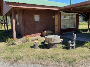 A rustic wooden building with a herringbone-patterned exterior, a wooden door, and a window with a grid pattern. - Patagonia Bordelago (Río Ibáñez)