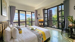 Een hotelkamer met een groot bed, een balkon met uitzicht en een zithoek.
