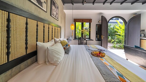Een hotelkamer met een bed, een ventilator, een ontbijtservering en uitzicht op het omliggende landschap.