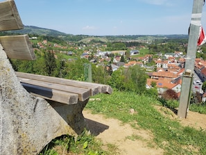 A stone bench overlooking a village with red-roofed houses and greenery. - Hotel Restaurant Stv Ckl (Schwanberg)