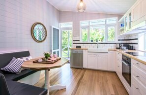 A modern kitchen with white cabinets, a wooden countertop, and a built-in dishwasher. - Franklin Cottage (Olinda)