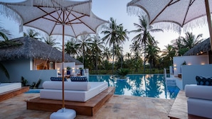Un espace aménagé au bord de la piscine, avec des chaises longues, des parasols et une vue dégagée sur la piscine.