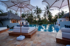Ein Poolbereich mit Liegestühlen, Sonnenschirmen und freiem Blick auf den Pool.