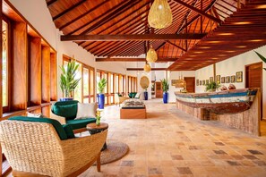 Eine geräumige Lobby mit hoher Decke, Holzbalken und einer Rezeption mit einem dekorativen Boot.