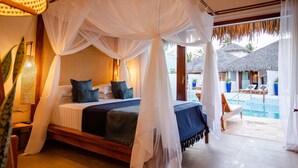 Un lit à baldaquin, un espace aménagé au bord de la piscine avec des chaises longues, et une vue sur un complexe hôtelier tropical.