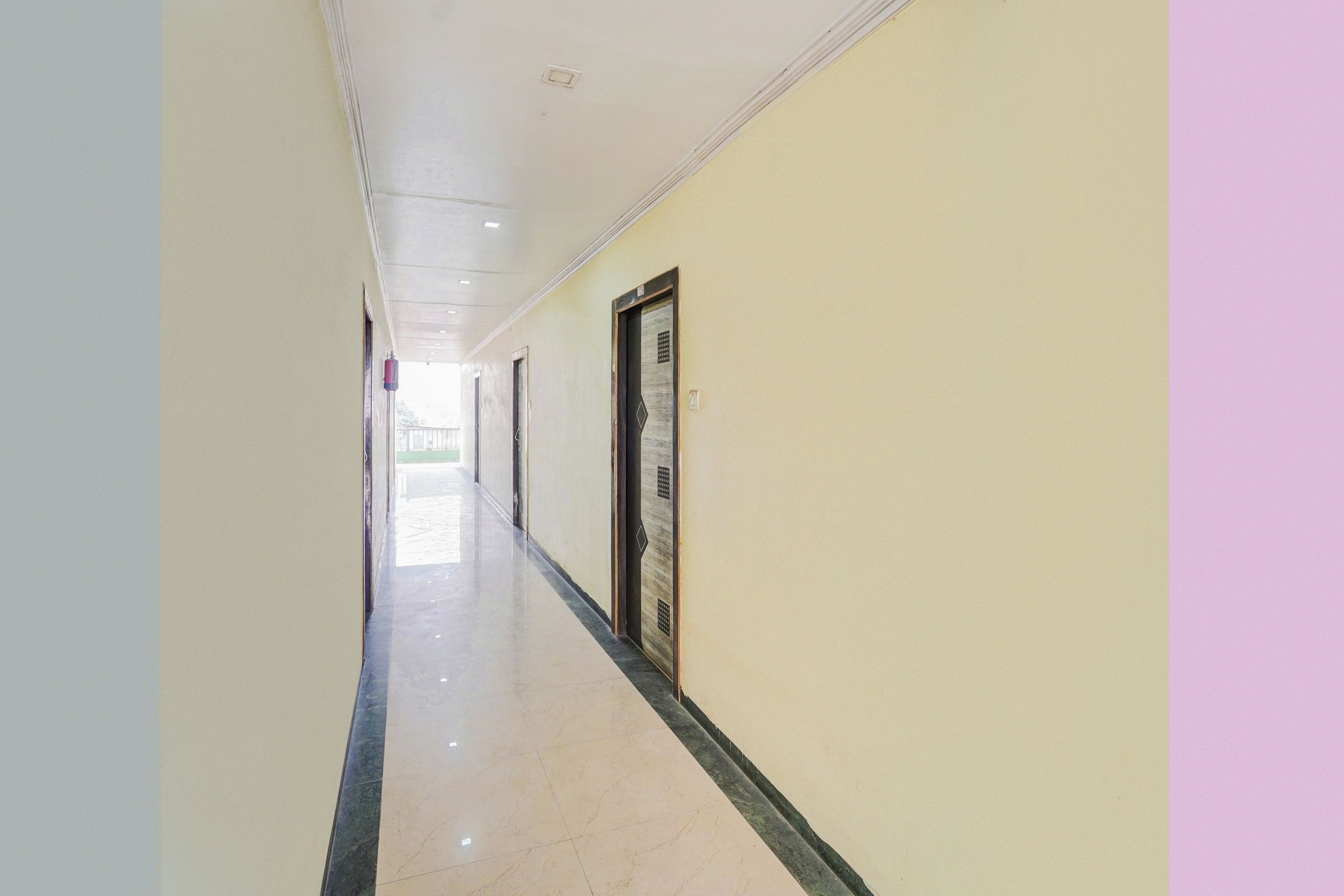 Un pasillo con puertas a un lado y una pared lisa al otro.