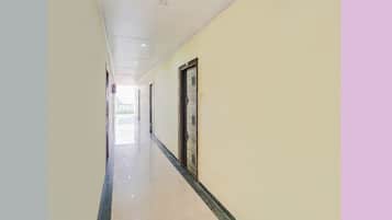 Un pasillo con puertas a un lado y una pared lisa al otro.