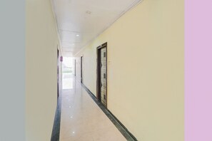 Un pasillo con puertas a un lado y una pared lisa al otro.