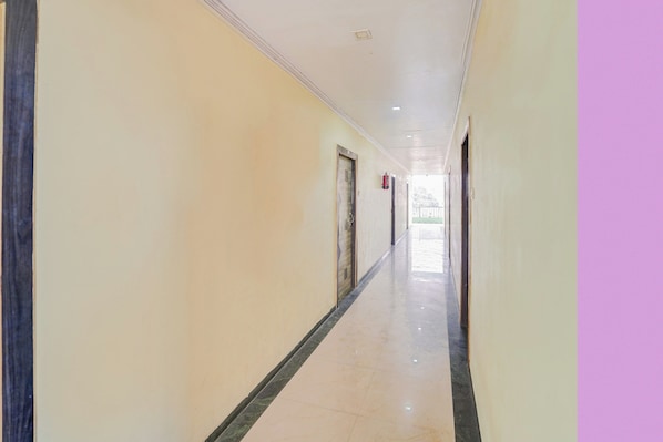 A long, narrow corridor with doors on one side and a plain wall on the other.