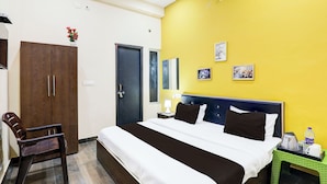 Habitación de hotel con cama, escritorio, silla, armario y puerta al baño.