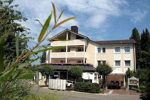 A multi-story hotel with a flat roof, balconies, and a garden area with outdoor seating. - Best Breakfast - Hotel Justina (Bad Woerishofen)
