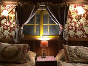 Een kamer met twee bedden, een nachtkastje met een lamp en een raam met gordijnen.