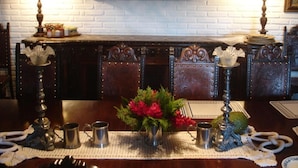 A dining table with a floral centerpiece, two candlesticks, and a white brick wall in the background. - Pousada Fazenda Pinhalzinho (Ribeirao Claro)