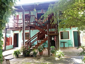 Escadaria de madeira em vários níveis que leva a um edifício com um terraço coberto de azulejos.