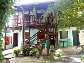 Escadaria de madeira em vários níveis que leva a um edifício com um terraço coberto de azulejos.