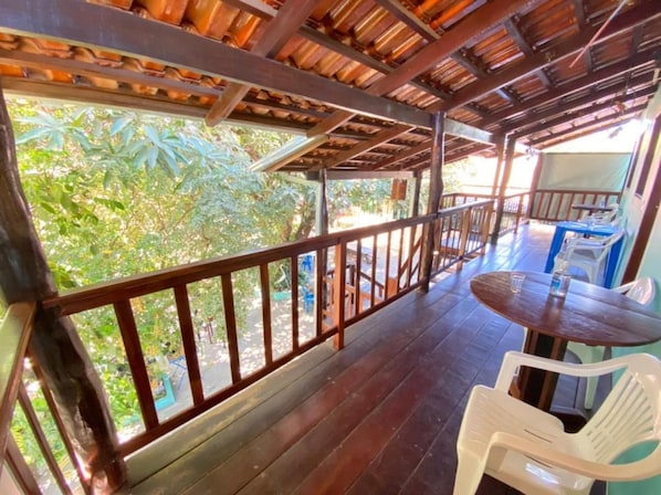 Um deck de madeira com guarda-corpo, uma mesa e cadeiras.