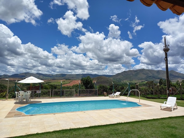 A swimming pool with a view of mountains in the background. - Pousada Tia Tuquinha (Piumhi)