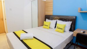 Ein Hotelzimmer mit Bett, Nachttisch, Sessel und Kleiderschrank.