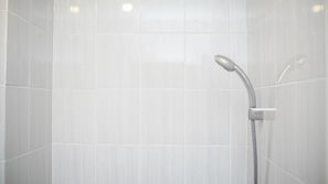 A shower with a handheld showerhead and a wall-mounted faucet.