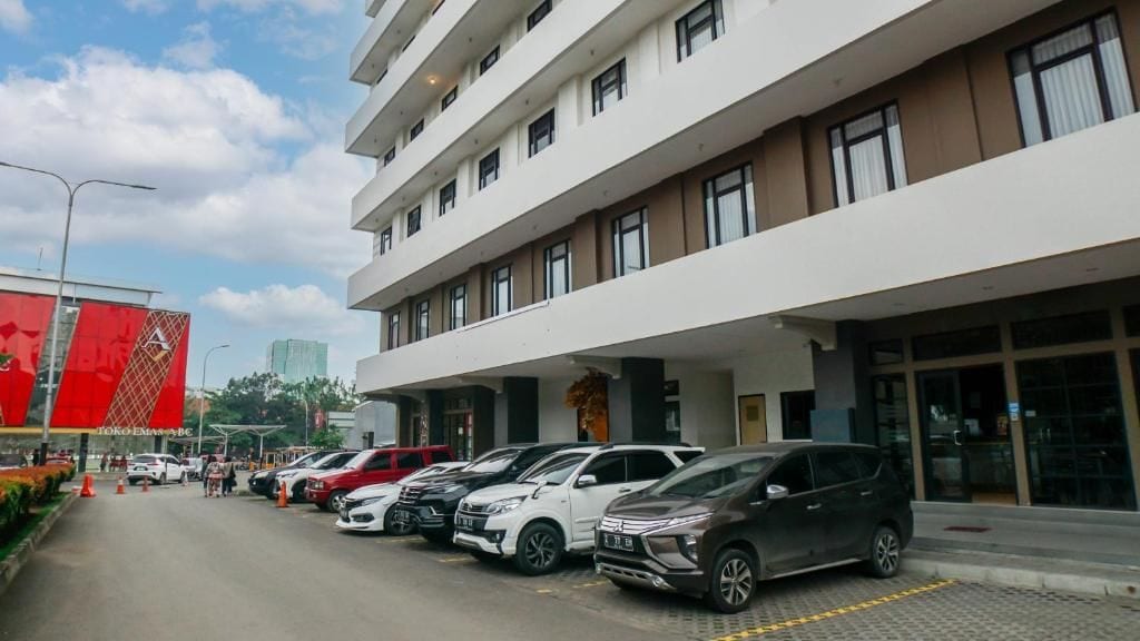 Un hotel de varios pisos con un estacionamiento al frente.