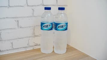 Two bottles of air mineral water on a wooden surface against a white brick wall.
