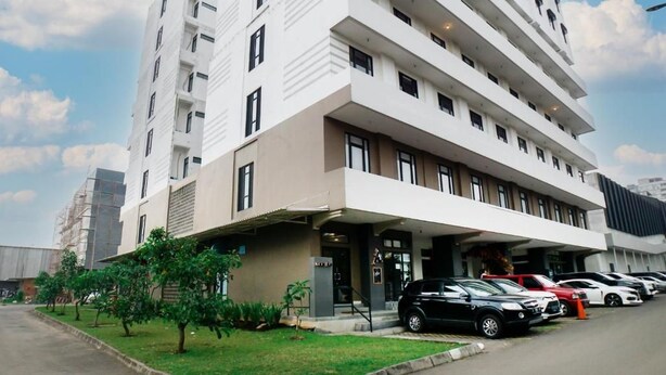 A multi-story hotel with a modern design, featuring a covered entrance and a parking area with several cars. - My Room at Paskal Hypersquare (Kota Bandung)