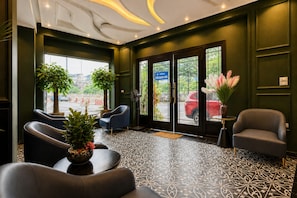 A hotel lobby with a reception desk, seating area, and large windows. - Premium Madelis Hotel (Hanoi)