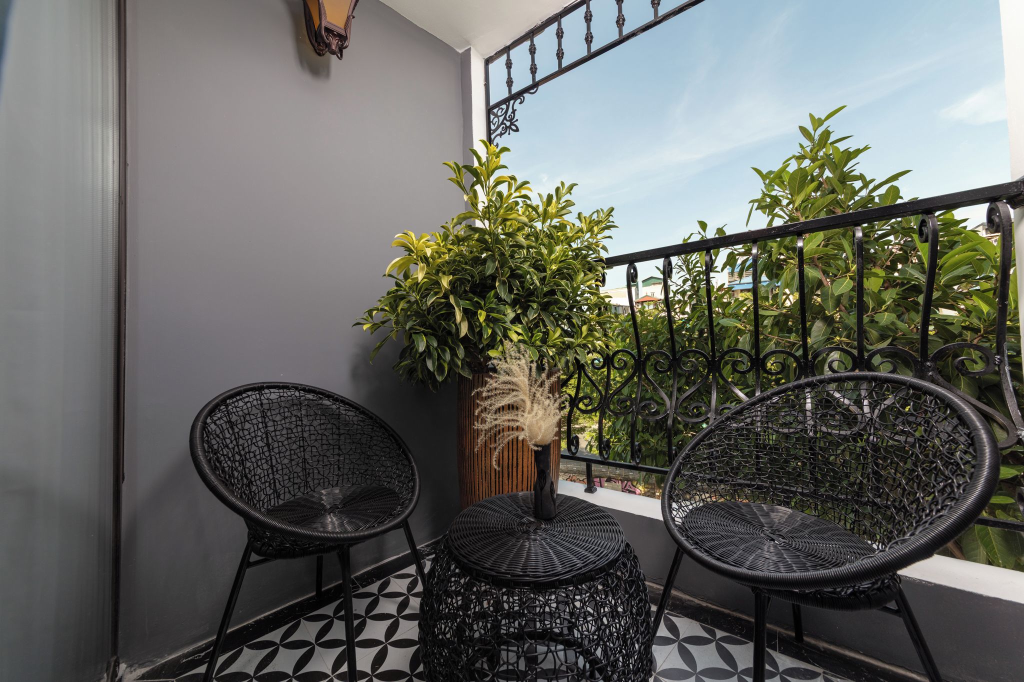 A balcony with two wicker chairs, a small table, and a potted plant.