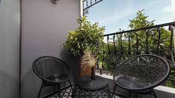 A balcony with two wicker chairs, a small table, and a potted plant.