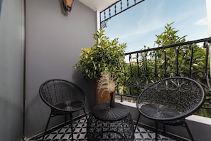 A balcony with two wicker chairs, a small table, and a potted plant. - Premium Madelis Hotel (Hanoi)