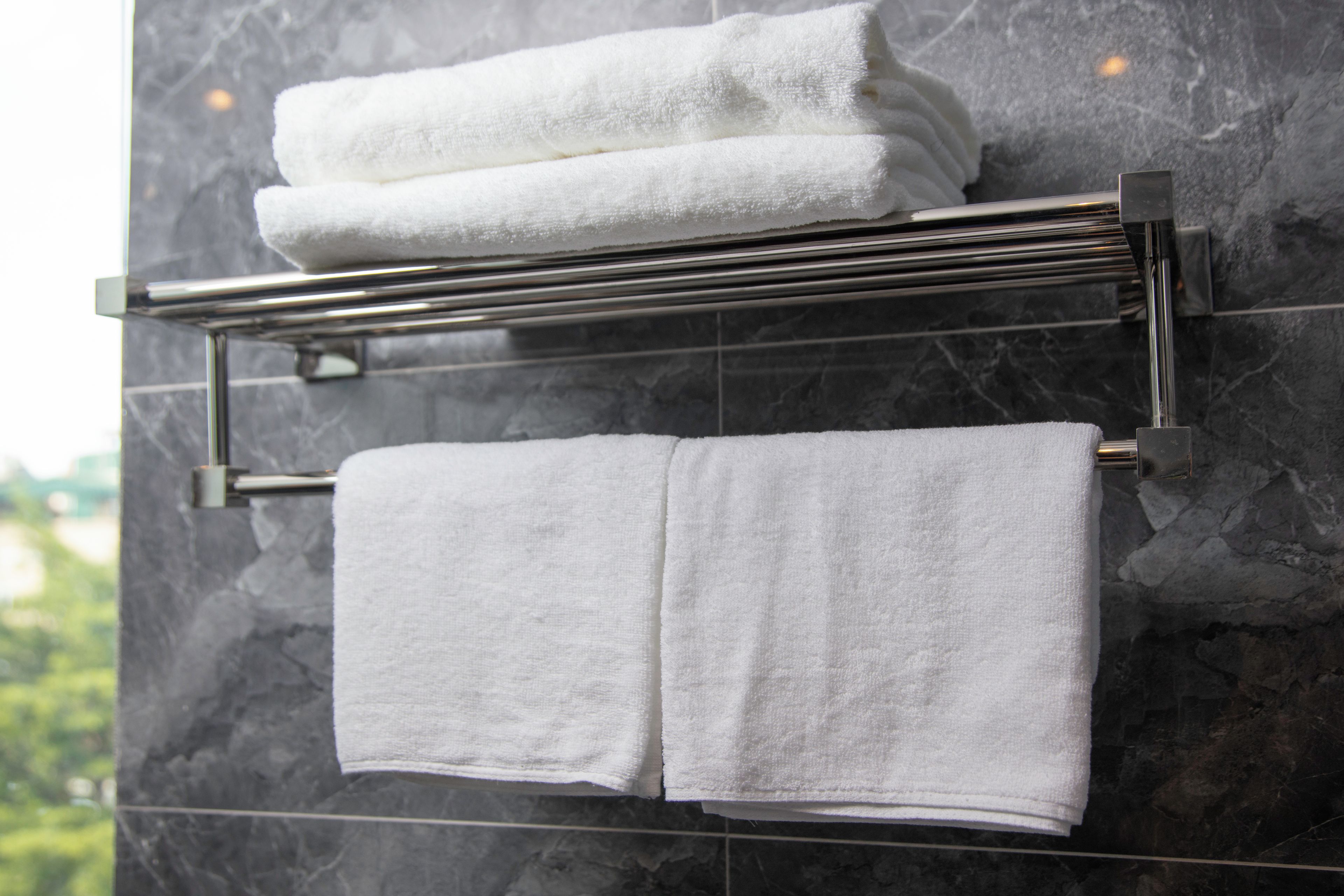 A bathroom with a towel rack holding two folded towels.