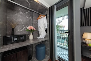 A bathroom with a marble wall, a black microwave, a vase with flowers, and a hanging robe. - Premium Madelis Hotel (Hanoi)