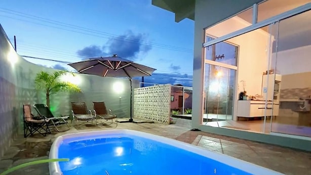 Piscina com superfície de água azul e límpida, cercada por um espaço de terraço com mobiliário de exterior.