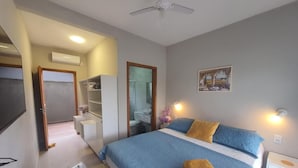 Quarto de hotel com cama, mesa de cabeceira e escrivaninha.