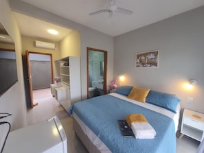 A hotel room with a bed, bedside table, and a desk. - Pousada Solari (São Francisco do Sul)