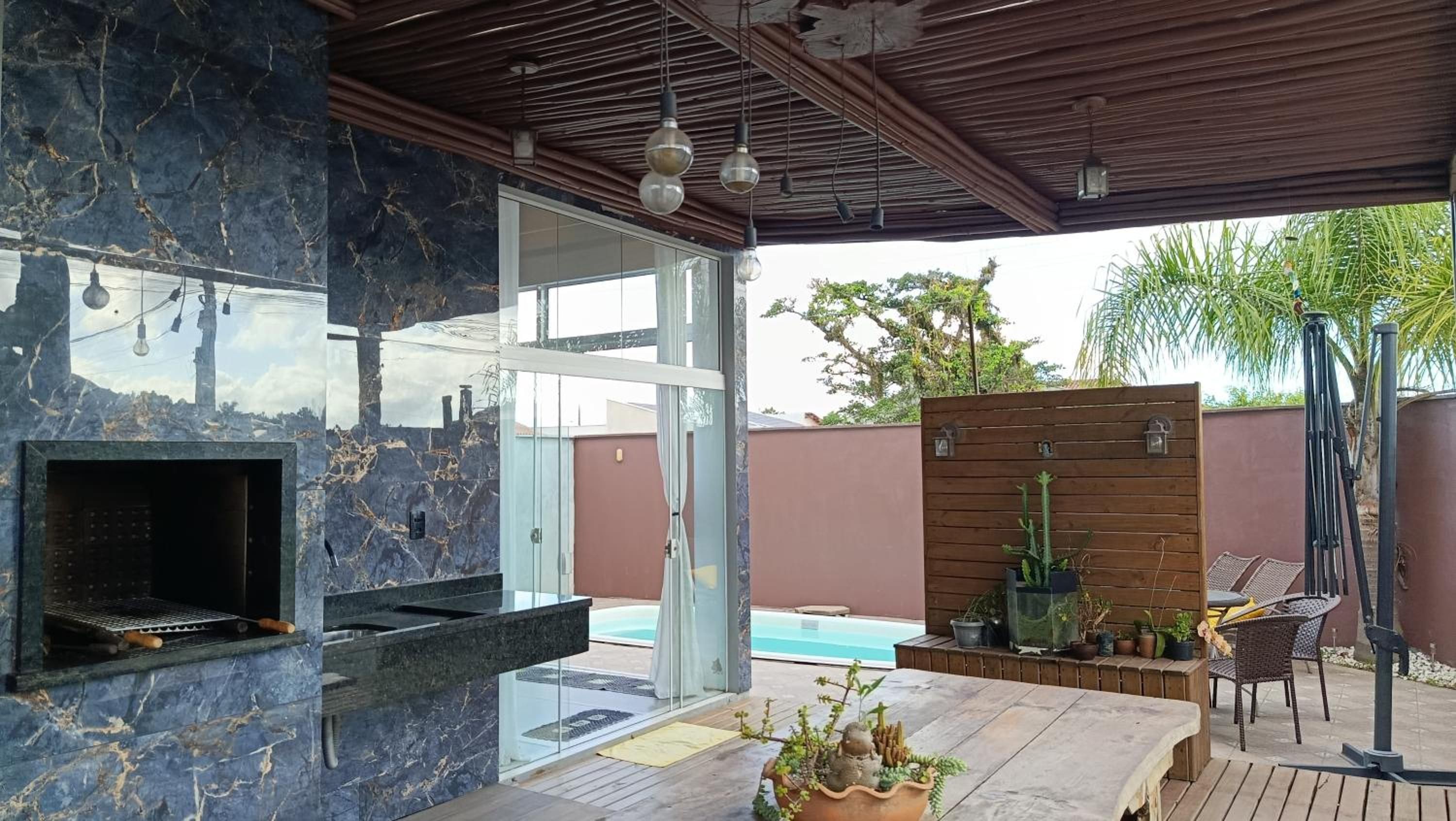 Um pátio ao ar livre com churrasqueira, piscina e um deck de madeira com cadeiras.