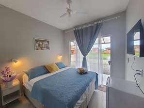 A bedroom with a bed, a nightstand, a wall-mounted TV, and a ceiling fan. - Pousada Solari (São Francisco do Sul)