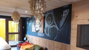A room with a bed, a large abstract painting on the wall, and a hanging light fixture. - Top Home Pousada (Caucaia)