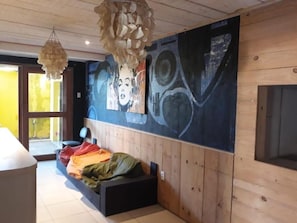 Ein Zimmer mit einem Bett, einem großen abstrakten Gemälde an der Wand und einer Pendelleuchte.