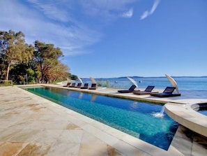 A rectangular pool with clear blue water, surrounded by lounge chairs and a stone deck. - Amarna Luxury Beach Resort (Nelson Bay)