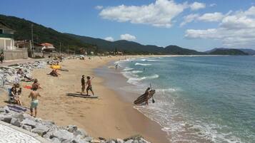 Una playa con gente, costa rocosa y cielo despejado.