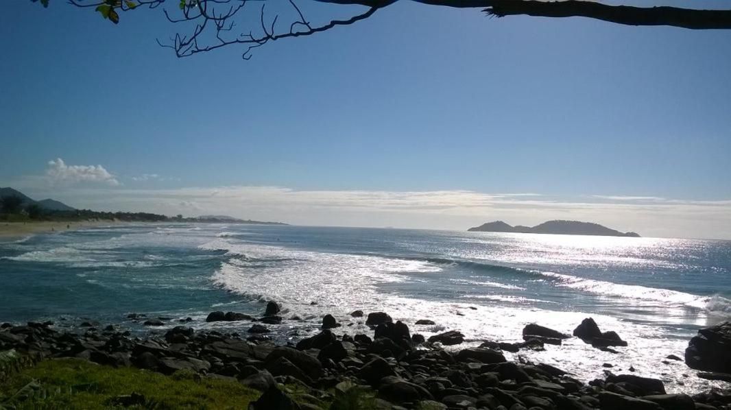 Un paisaje costero con un primer plano rocoso, una playa y un cielo despejado.